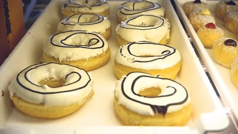 Delicious sweet donuts in different glazes lie on the display case. slow motion Stock Footage 86891311