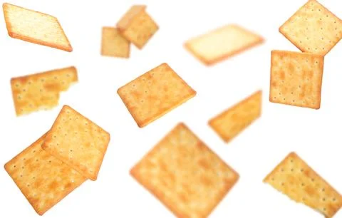 Delicious thin crispy crackers, broken crackers falling on white background. Stock Photos