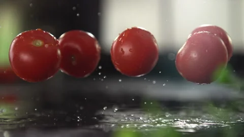 Delicious Tomatoes fall in slow motion onto a black slate.. Stock Footage 160927872