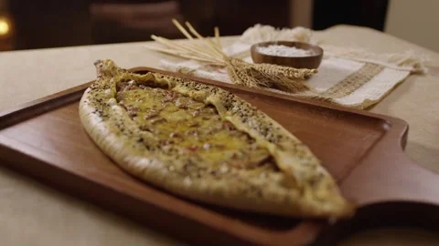 Delicious Turkish pide with melted cheese and meat resting on a wooden board Stock Footage 345633957