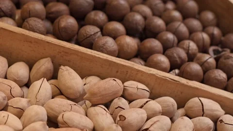 Delicious unshelled pistachio nuts in shell and macadamia nut in wooden crates Stockbeeldmateriaal 217758908