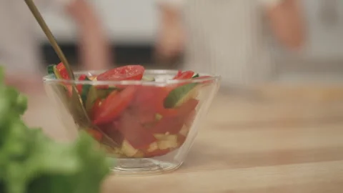 Delicious vegetables salad on kitchen table, silhouette of people in background Stock Footage 309079552