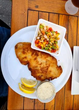 Delicious warm breaded schnitzel with vegetable garnish in a bowl with two slice Stock Photos