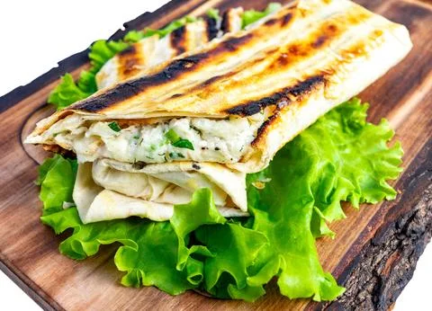 Delicious wrap made of grilled flatbread and fresh greens served on a wooden Stock Photos