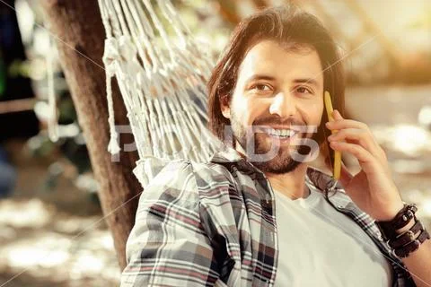 Delighted bearded man answering a phone call Stock Photos