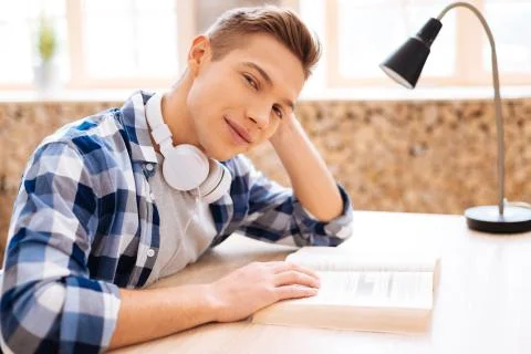 Delighted boy reading a book at the table Stock Photos