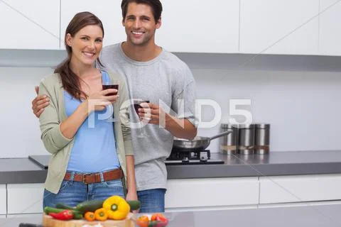 Delighted couple clinking their glasses of red wine Stock Photos