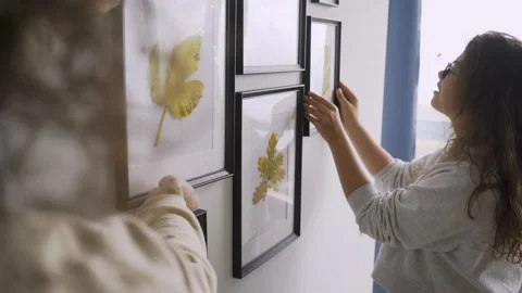 Delighted couple hangs wooden frames of different size Stock Footage 148020916