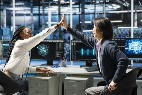Delighted engineers celebrating in data center after finishing coding 库存照片