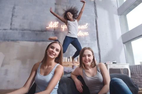 Delighted girl jumping and having fun with friends Stock Photos