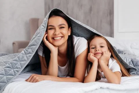 Delighted mother lying in bed with a child Stock Photos