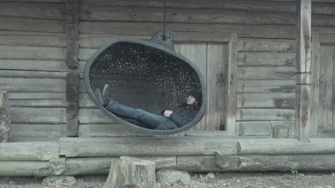 Delighted relaxed guy lies in large black swing in museum Stock Footage 146718329