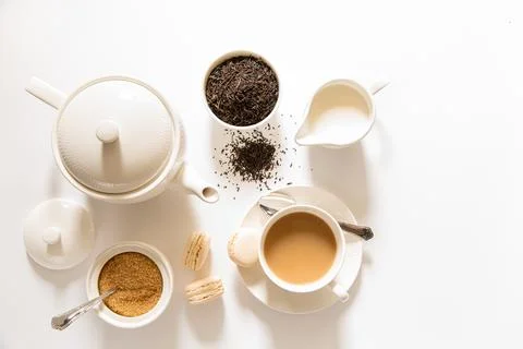 Delightful afternoon tea setup featuring tea pot, cup, sugar, and fresh macarons Stock Photos