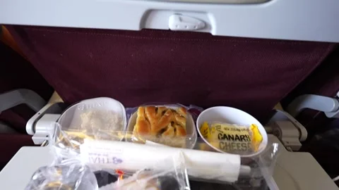 A delightful in flight meal with a box set, water, and desserts neatly arranged Stock Footage 301530156