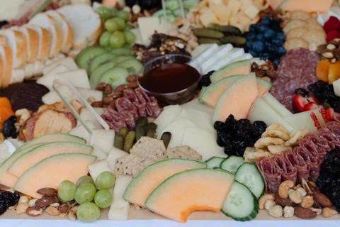 Delightful spread of assorted cheeses, meats, fruits, and nuts arranged Stock Photos