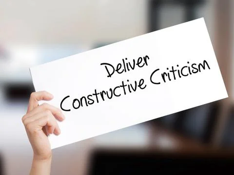 Deliver Constructive Criticism Sign on white paper. Man Hand Holding Paper wi Stock Photos
