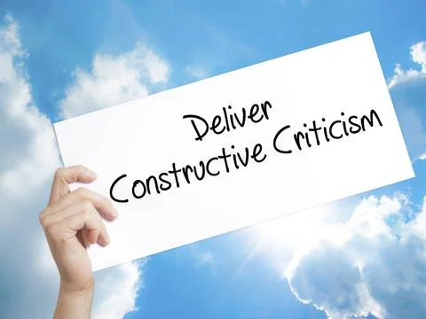 Deliver Constructive Criticism Sign on white paper. Man Hand Holding Paper... Stock Photos