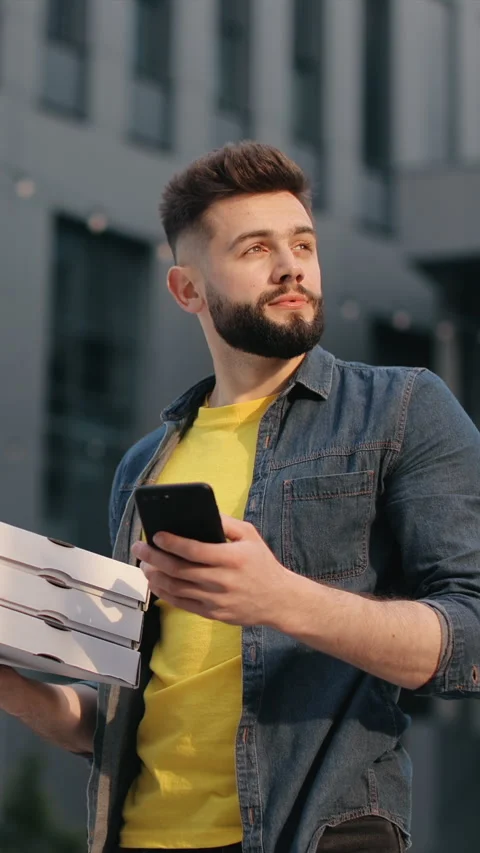 Delivering delicious pizza while checking the order on a sunny city street Stock Footage 337151952