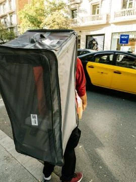 Delivery bag with multiple Amazon boxes while crossing busy street Stockfoto's