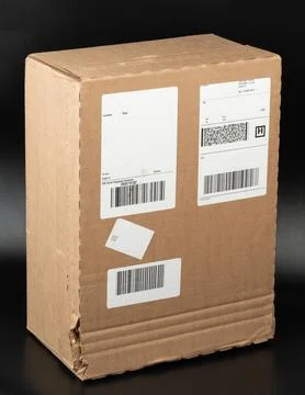 Delivery box placed on dark surface with shipping labels attached Stock Photos