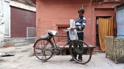 Delivery boy with bicycle sorting newspapers at street in Varanasi. Stock Footage 50377373