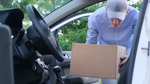 Delivery courier loads cardboard boxes with a parcel into a car Stock Footage 156951593