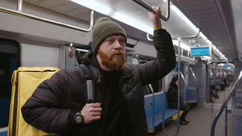 Delivery to customers. Hand-held camera. Brutal bearded courier rides the subway Stock Footage 236089348