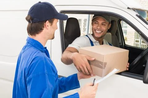 Delivery driver handing parcel to customer in his van 스톡 사진