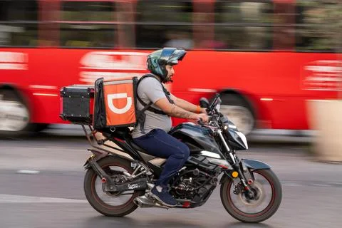 Delivery driver on motorcycle speeding through urban Zapopan city street Stock-Fotos
