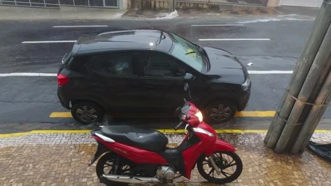 . A delivery driver's red motorcycle and a ride-hailing vehicle parked Stock Footage 323310064