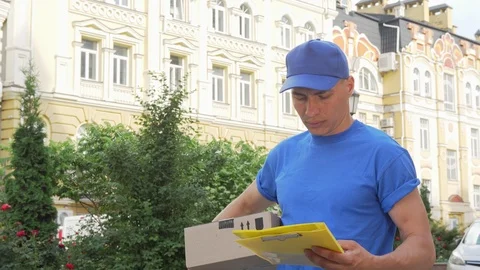 Delivery guy with cardboard box looking for the house of recepient client Video stock 115168677