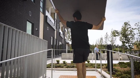 Delivery guy carrying a large piece of furniture into a townhouse. Stock Footage 102352126