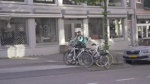Delivery Guy Deliveroo biking through Amsterdam Stock Footage 130209515