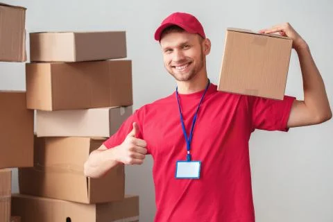 Delivery guy isolated on white wall standing holding box on shoulder looking Stock Photos
