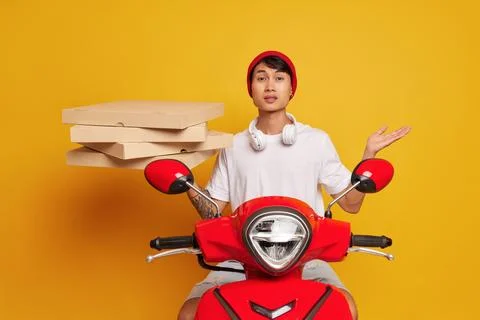 Delivery guy in red hat and white tshirt holding pile pizza boxes in one hand Stock-Fotos