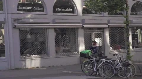 Delivery Guy Thuisbezorgd biking through Amsterdam Stock Footage 130237027