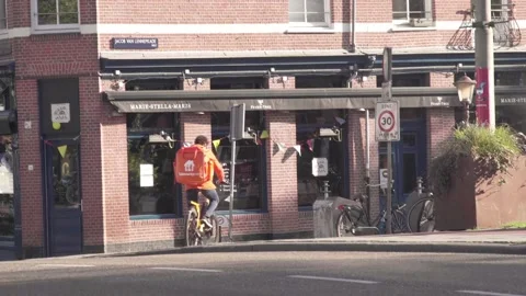Delivery Guy Thuisbezorgd biking through Amsterdam Stock Footage 130237061
