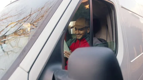 Delivery Guy Wearing A Cap Sitting In The Front Seat Of The Van - Parcel 스톡 동영상 155720558