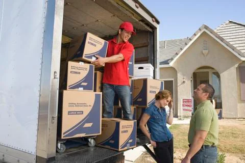 Delivery Man And Couple Unloading Moving Boxes From Truck Stock Photos
