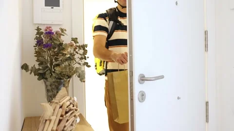 Delivery man with a backpack handing a paper bag at the door Stock Footage 318096104