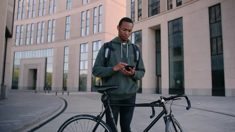 Delivery man on a bicycle against the background of a business center Stock Footage 254100302