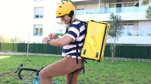 Delivery man on a bike checking his smartwatch Stock-Footage 318096147