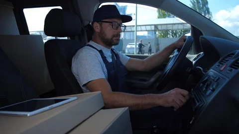 Delivery man in cap checking route sitting in car Stock Footage 114911887