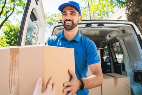 Delivery man carrying packages while making home delivery. Stock Photos