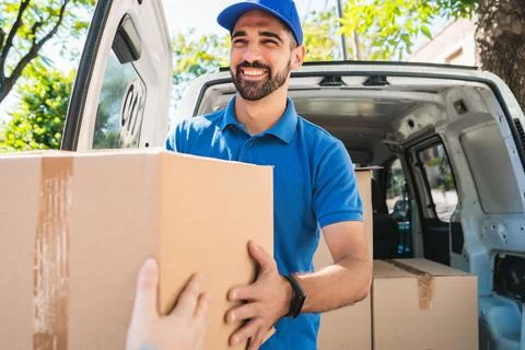 Delivery man carrying packages while making home delivery. Stock Photos