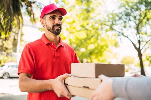 Delivery man carrying packages while making home delivery. Stock Photos