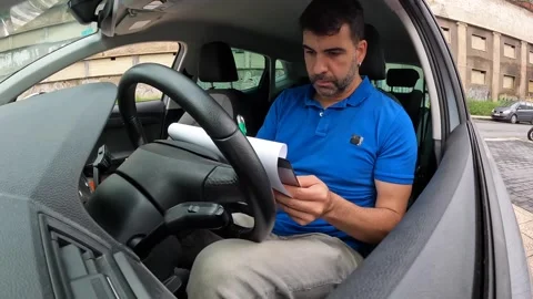 Delivery man checking a package sitting inside a car Stock Footage 286408441