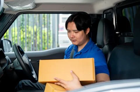 A delivery man is checking packages in his van before driving to deliver th.. Stock Photos