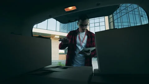 Delivery man is checking parcels in the trunk of a car Stock Footage 133445164