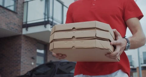 Delivery man close-up carrying three boxes withhot pizza walking in the street Stock Footage 114941638